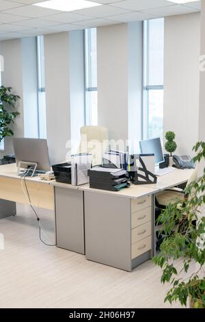Grand bureau moderne avec deux bureaux, ordinateurs, documents et autres fournitures pendant la pause Banque D'Images