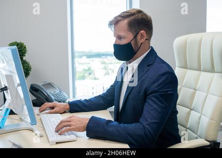 Jeune ouvrier caucasien de collier blanc travaillant devant l'ordinateur dans le bureau Banque D'Images