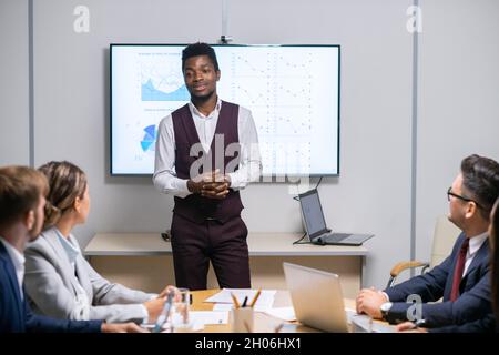 Un jeune coach d'affaires qui a du succès se tient devant le public lors d'un discours sur tableau blanc Banque D'Images