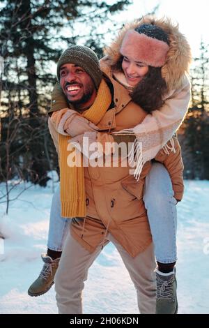 Jeunes joyeux dates interculturelles en hiver s'amuser dans le parc le jour d'hiver Banque D'Images