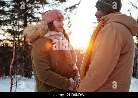 Les jeunes dates amoreuses se tiennent à la main le jour d'hiver tout en se tenant devant l'appareil photo Banque D'Images