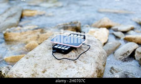 Portable alimenté solaire usb charge le téléphone et est situé sur un rocher sur la plage. Énergies alternatives. ECO. Banque D'Images