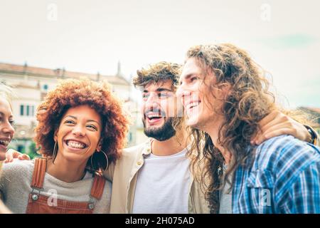 Groupe d'amis heureux rire ensemble - Groupe de mecs multiraciaux s'amuser dans la rue de la ville - Portrait de quatre étudiants de culture différente Banque D'Images