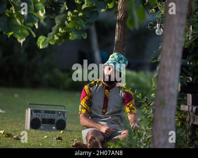 Homme déprimé assis sur l'herbe dans le parc et fumer Banque D'Images