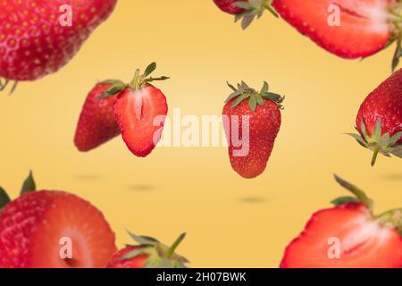 Composition créative avec des fraises mûres flottantes et leveuses sur fond jaune.Vitamines, concept d'aliments frais et sains.Idée de fruit minimale.SLIC Banque D'Images