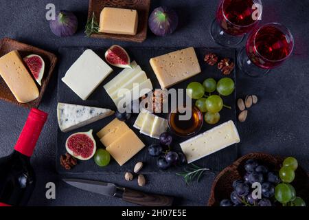 Variétés de fromage, raisins, figues et noix sur une plaque d'ardoise.En-cas au vin pour une fête de vacances.Vue de dessus Banque D'Images