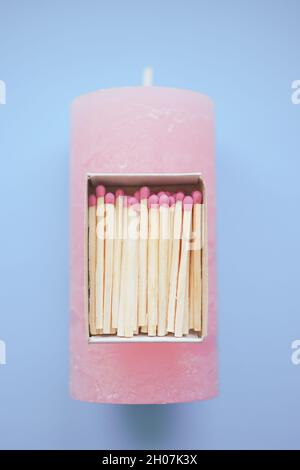 Allumettes dans une boîte ouverte sur une bougie rose pâle sur la table bleue Banque D'Images