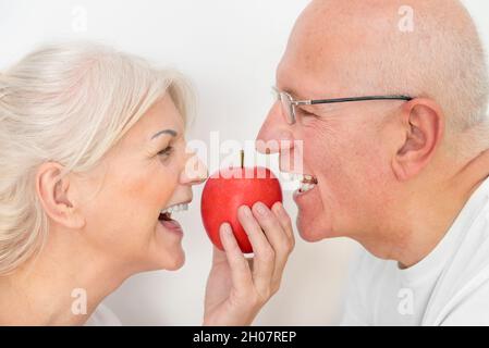 Deux personnes âgées tenant une pomme.Concept de dents saines et fortes Banque D'Images