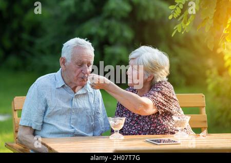 Couple senior assis en garde et en train de manger de la crème glacée dans des bols en verre Banque D'Images