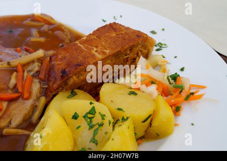 délicieux plat autrichien composé d'un rôti de porc, de pommes de terre et d'un morceau de tarte nappé d'une grande portion de sauce à la viande Banque D'Images