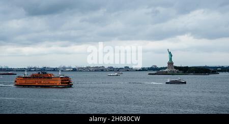 Le ferry de Staten Island navigue par Lady Liberty par une journée nuageux. Banque D'Images