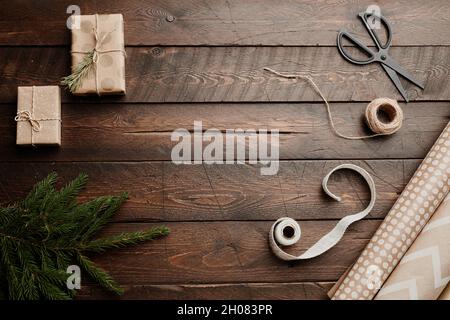 Vue de dessus arrière-plan de Noël avec table en bois et fournitures de papier cadeau rustique, espace de copie Banque D'Images