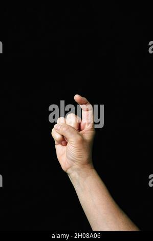 Photo verticale d'une main montrant la lettre X sur un fond sombre Banque D'Images