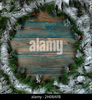 Vue en hauteur d'une couronne couverte de neige avec de petits cônes de pin dans la bordure circulaire sur des planches de bois vieillies bleues pour les vacances d'hiver de Noël ou Banque D'Images