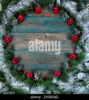 Vue en hauteur d'une couronne couverte de neige avec bougies rouges dans le cadre circulaire sur des planches de bois vieillies bleues pour les vacances d'hiver de Noël Banque D'Images