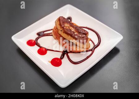 Pintxos artisanaux ou tapas de foie gras sur un toast avec glaçure balsamique et confiture d'oignons sur une assiette dans un restaurant à Pampelune, Espagne Banque D'Images