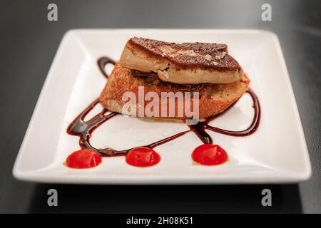 Pintxos artisanaux ou tapas de foie gras sur un toast avec glaçure balsamique et confiture d'oignons sur une assiette dans un restaurant à Pampelune, Espagne Banque D'Images