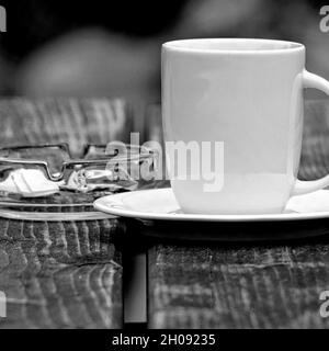 Photo en niveaux de gris d'une tasse de café sur la table Banque D'Images