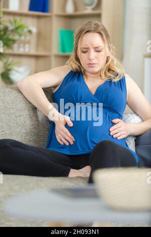 femme enceinte s'asseoir sur le canapé inquiet Banque D'Images