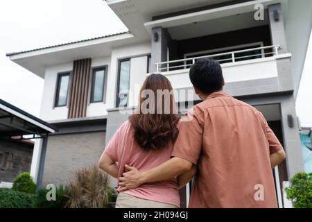 jeune couple debout à l'extérieur et regardant leur maison Banque D'Images