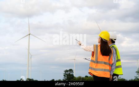 jeune équipe d'ingénieurs travaillant avec le rapport dans le presse-papiers contre la ferme éolienne Banque D'Images
