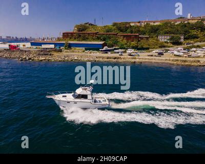 Un bateau blanc va à plein régime le long de la rive.Photo du drone, du côté. Banque D'Images