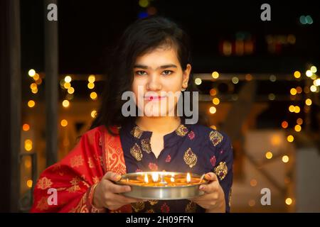 Portrait de Happy Young indian magnifique femme tenir plaque/thali avec diya/argile lampes à l'huile portant la robe traditionnelle, célèbre diwali, festival de lumières Banque D'Images