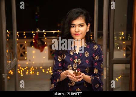 Portrait de Happy Young indian magnifique femme tenant diya / argile lampes à l'huile portant des vêtements traditionnels, célébrant diwali, intérieur.jolie femme dans ethnique Banque D'Images