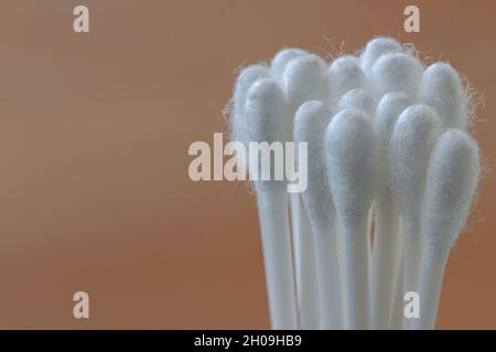 Un groupe de bourgeons blancs en coton avec matière plastique, isolés sur fond marron, le concept de santé, de beauté et d'hygiène Banque D'Images