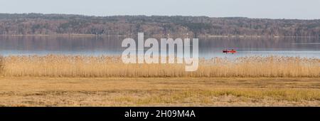 Seeseiten, Allemagne - 23 févr. 2021: Paysage pittoresque à Starnberger Voir avec canoë rouge et roseaux.Format Panorama. Banque D'Images