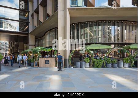 Les gens qui marchent dans l'arcade Bloomberg et qui déjeunent en plein air dans les restaurants du siège de Bloomberg.Ville de Londres, Angleterre, Royaume-Uni Banque D'Images