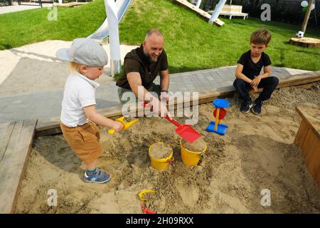 '16.07.2021, Allemagne, Brême, Brême - ouverture d'un centre de garderie : le père joue avec son fils dans la sandbox, le frère aîné est assis à côté de lui.Remarque : v Banque D'Images