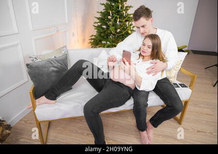 Un jeune couple caucasien prend un selfie sur le canapé à l'heure de noël Banque D'Images