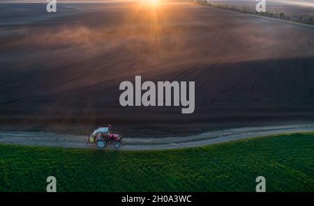 Image aérienne d'un tracteur roulant sur route de terre avec équipement pour la pulvérisation de sol, pousse à partir de drone Banque D'Images