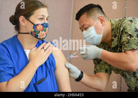 AGANA HEIGHTS, Guam (janv4, 2021) – l'hôpital Corpsman de 2e classe Mark Forrey, affecté à l'hôpital naval américain de Guam (USNH Guam), administre un vaccin Covid-19 au Lt. Cmdr.Allison Wessner, pédiatre affecté à l'USNH Guam.Le DoD a reçu une quantité limitée de doses de vaccin COVID-19 lors de son envoi initial et administre actuellement le vaccin au personnel de la phase 1a, y compris les fournisseurs de soins de santé et le personnel de soutien, les services d'urgence et le personnel de sécurité publique. Banque D'Images