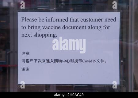 Un panneau bilingue, écrit en anglais et en chinois, indique aux clients qu'ils ont besoin d'une carte de vaccination pour y participer.EON Mall 1, Phnom Penh, Cambodge.9 octobre 2021.© Kraig Lieb Banque D'Images