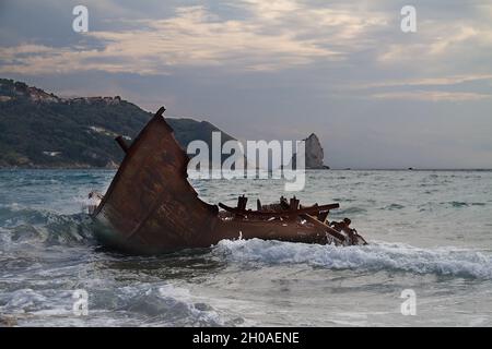 Vagues éclaboussant sur l'épave rouillée d'un bateau de pêche cassé et toronné Banque D'Images