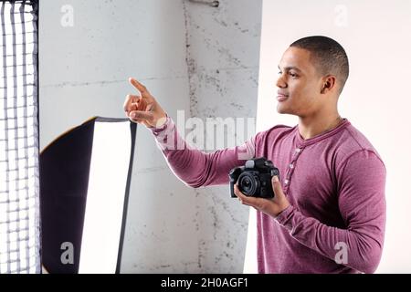 Jeune photographe noir donnant des instructions pendant un tournage dans son studio en pointant avec son doigt comme il parle Banque D'Images