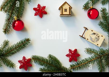 Arrière-plan du nouvel an ou de Noël avec branches en épicéa, boules rouges et flocons de neige. Jouets en bois. aménagement à plat. Vue du dessus. Fond blanc Banque D'Images