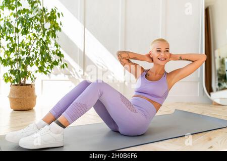 Sports domestiques.Femme athlétique faisant des exercices sur le tapis de yoga, renforçant ses muscles abs à la maison Banque D'Images