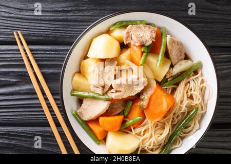 Nikujaga est fait à partir de viande finement tranchée mâchée avec des pommes de terre, des carottes et des oignons dans une sauce à base de soja légèrement sucrée dans un bol sur le tabl en bois Banque D'Images