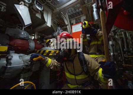 210116-N-NC885-1092 MER D'OMAN DU NORD (JANV16, 2021) technicien en systèmes d'information 2e classe Jakob Aganon, de Las Vegas, (à gauche) et spécialiste des services au détail 3e classe Juan Bueno Barrios, de Pembroke Pines, FLA recherche un feu simulé lors d'un forage de quartier général à bord du destroyer de missile guidé USS Sterett (DDG 104).Sterett fait partie du Nimitz Carrier Strike Group et est déployé dans la zone d'opérations de la 5e flotte des États-Unis pour assurer la stabilité et la sécurité maritimes dans la région centrale, reliant la Méditerranée et le Pacifique à travers l'océan Indien occidental et trois critiques Banque D'Images