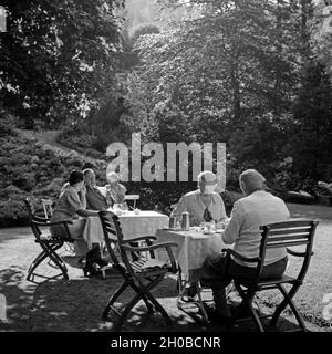 Männer und Frauen un Außengastronomie sitzen und Tischen bei Triberg im Schwarzwald, Deutschland 1930 er Jahre. Les hommes et les femmes assis sur les tables d'une gastronomie plein air près de Triberg en Forêt-Noire, Allemagne 1930. Banque D'Images