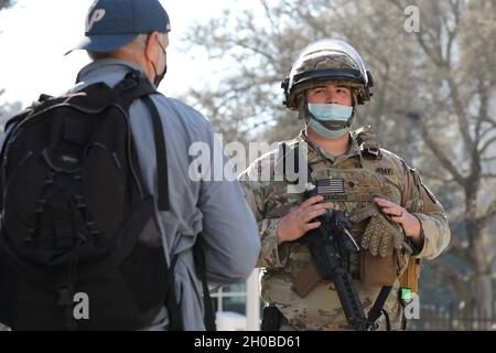 SPC de l'armée américaine.Taylor S. Sanders, de la 270e compagnie de police militaire, 185e Bataillon de police militaire, 49e brigade de police militaire, Garde nationale de l'armée de Californie, maintient sa posture militaire en tant que visiteur pose des questions le 18 janvier 2021, au Capitole de l'État à Sacramento, en Californie.CAL Guardmen continue de fournir une sécurité supplémentaire dans les installations fédérales et d'état alors que la nation se prépare à l'inauguration du président nouvellement élu Biden le 20 janvier. Banque D'Images