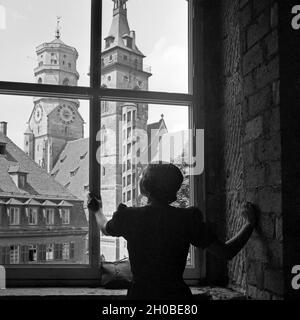 Eien Frau blickt auf die durch ein Fenster am Schillerplatz Schwanenburg à Stuttgart, Deutschland 1930er Jahre. Une femme regardant par la fenêtre la collégiale à la place Schillerplatz à Stuttgart, Allemagne 1930. Banque D'Images