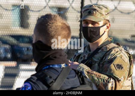 Un soldat de la Garde nationale de l'armée de l'Oklahoma s'entretient avec un officier de la police du Capitole des États-Unis pendant son service près du bâtiment du Capitole des États-Unis, le 19 janvier 2021.Au moins 25,000 hommes et femmes de la Garde nationale ont été autorisés à mener des missions de sécurité, de communication et de logistique à l'appui des autorités fédérales et de district jusqu'à la 59e inauguration présidentielle. Banque D'Images