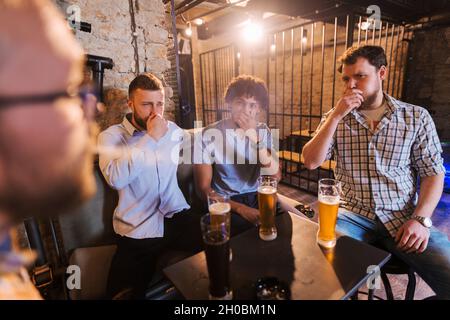 Homme fumant au pub et ses amis toussant.Concept anti-fumeurs. Banque D'Images