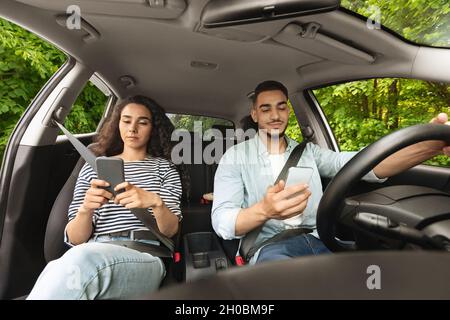 Arabe homme et femme utilisant un smartphone lors de voyages en voiture Banque D'Images
