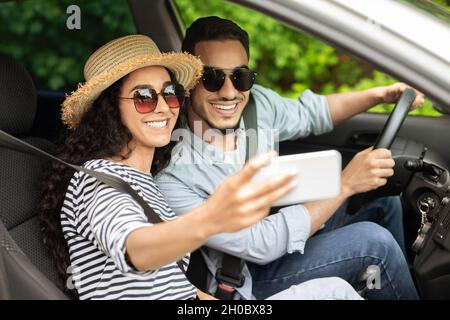 Un jeune couple heureux prend le selfie à l'intérieur de la voiture Banque D'Images