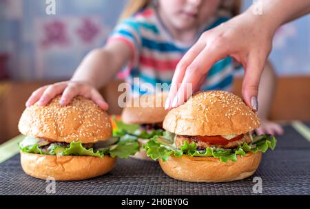 Main de petit enfant et main de mère sur des hamburgers faits maison. Le concept de la cuisine délicieuse à la maison avec votre enfant Banque D'Images